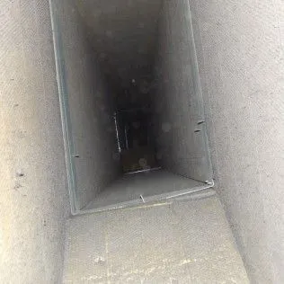 Dark rectangular ventilation shaft or duct interior, gray walls fading into shadow.